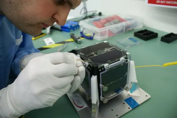 Me gluing one of the last bolts on the solar panel of FUNcube, a little dab of epoxy glue applied with a toothpick in the clean room