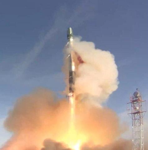 Close-up of the DNEPR rocket right after launch with a big plume of smoke and a metal communications tower visible