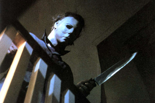 Michael Myers from John Carpenter's Halloween. He's looking over a railing, down the stairs while holding his iconic knife.