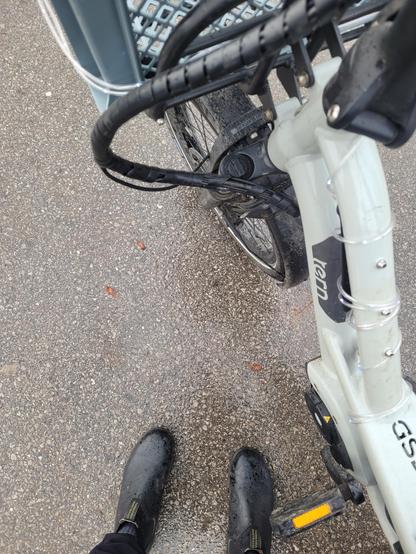 A photo of my boots, my bike, and wet pavement 
