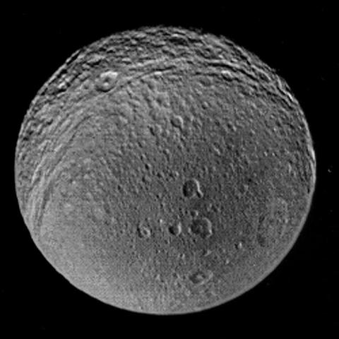 A Voyager 2 image of Tethys showing the odd shading in Penelope. Here the bright sunlit wall is darkened as seen in other views and the sunlight and dark surface nearly cancel out. The other nearby craters are also affected. The crater at the left end of the row of three should have a sunlit left (west) wall. It looks dark which must be the albedo effect. The other craters near the middle should have no shading, the Sun is overhead.