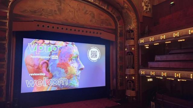 Zicht op grote zaal van Tuschinski theater Amsterdam, op het doek: "vpro reviewdag - welkom"