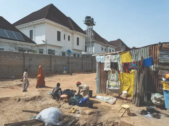 Children washing clothes in a slum settlement outside the security wall of a luxury estate in Abuja. 

Photo: Nick Hannes/Panos