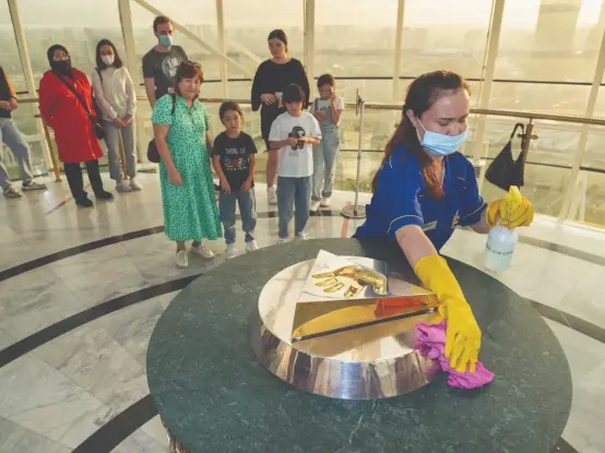 A woman cleaner rubs around the golden cast of the hand of former president Nursultan Nazarbayev in Bayterek Tower, Astana, while visitors stand in line to put their hands in the cast.

 Photo: Nick Hannes/Panos