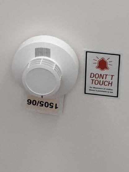 Rauchmelder mit Hinweisschild mit Schreibfehler "DONT'T TOUCH"