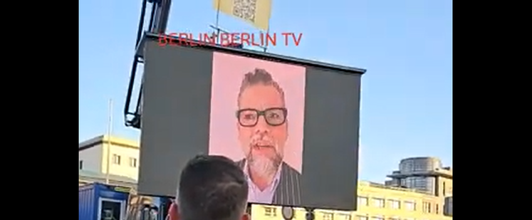 Auf einer Video-Leinwand wird das Gesicht von Ken Jebsen gezeigt.