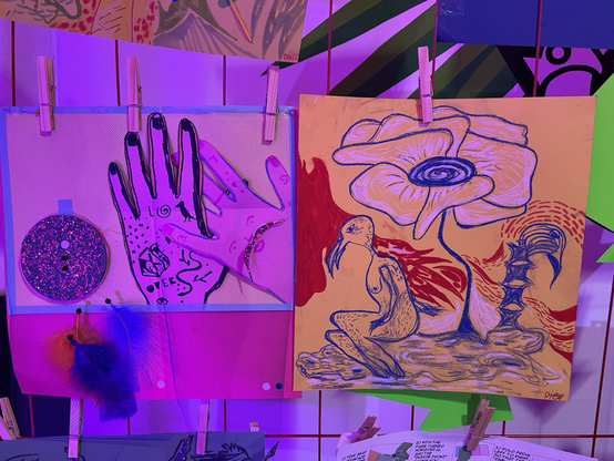 art hanging from the railing. one picture is featuring a hand, under it are feathers. the other features a bird like creature sitting under a giant flower.