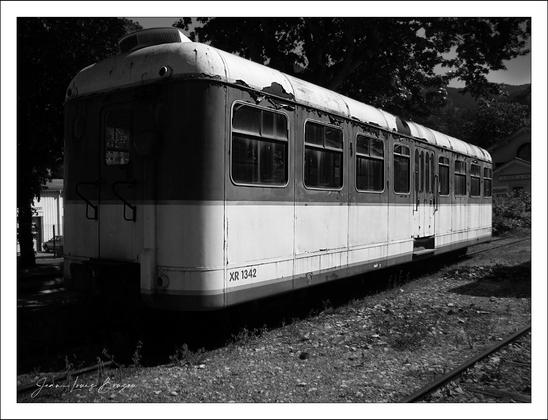 Black and white photography of an old dilapidated wagon on a railway...