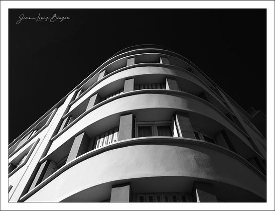 Black and white photograph of a building facade with balconies and window...