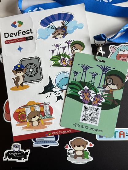 A collection of colorful stickers and a badge related to DevFest Singapore 2024. The stickers feature cartoon otters in various activities, along with tropical plants. The badge includes a QR code and branding for GDG Singapore. Pasted on a laptop is a 2023 devfest sticker.
