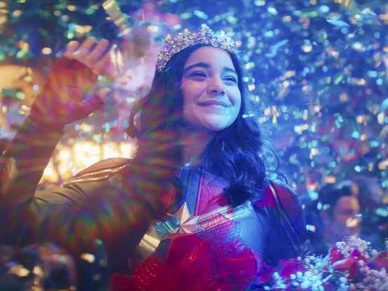 Image of Iman Vellani as Kamala Khan from the scene in the first episode of the first season of Ms. Marvel on Disney Plus where Kamala is daydreaming of winning the Captain Marvel cosplay contest at AvengerCon.