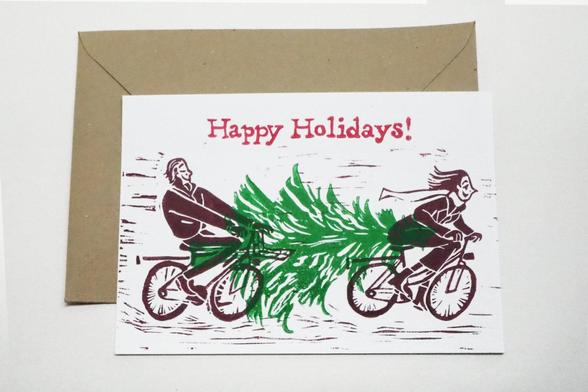 The hand printed lino cut holiday card “Bicycles” with behind it the envelope in recycled paper.