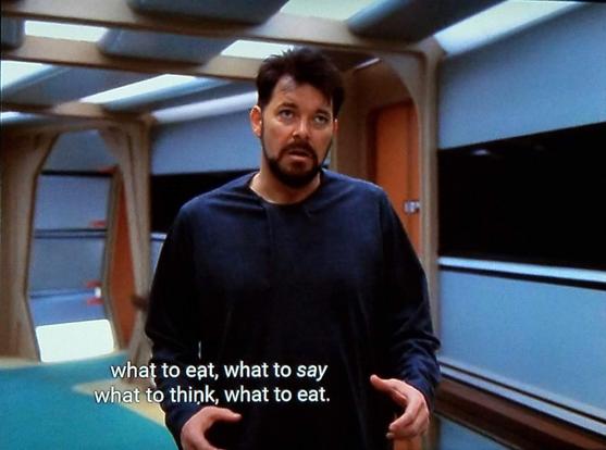 Star Trek The Next Generation scene. We're on ship and in a beautifully carpeted and panelled corridor. William T. Riker, usually in his red uniform, is shown here in his pajamas wandering the hall. He looks bedraggled and shluffy and a slightly deranged. 
Closed caption reads, "what to eat, what to say, what to think, what to eat."