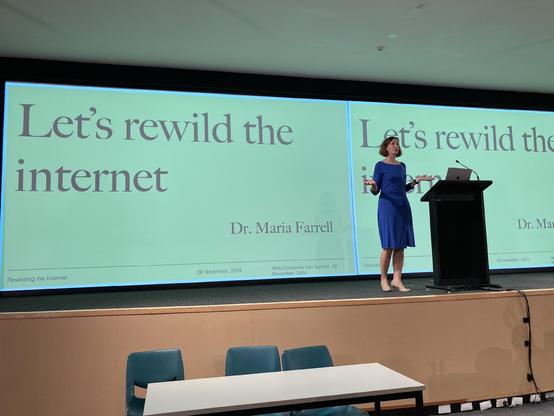 Maria on stage in front of her title slide Let's Rewild The Internet 
