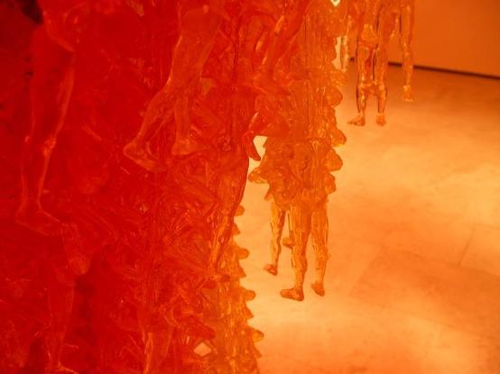 a close-up of the figures, they are men sitting on each others shoulders , in vertical strands, thousands of them 