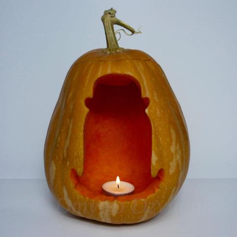 Cousin Itt from The Addams Family, diminutive, floor-length hair being, wearing a bowler hat is depicted on a carved pumpkin. Pumpkin with a tealight candle inside.