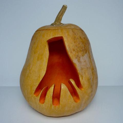 Thing T. Thing from The Addams Family, disembodied hand, running on his fingertips is depicted on a carved pumpkin.