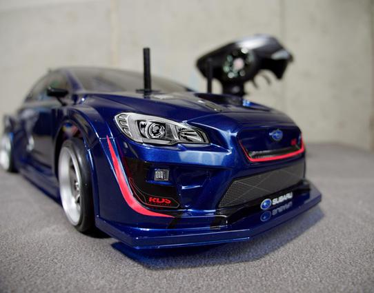 low, headlight level front view of an RC car, painted in a metallic Blue with tinted windows, and markings of a Subaru WRX STI