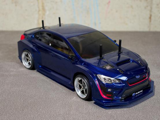 Front right 3/4 view of an RC car, painted in a metallic Blue with tinted windows, and markings of a Subaru WRX STI