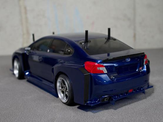 left rear view of an RC car, painted in a metallic Blue with tinted windows, and markings of a Subaru WRX STI