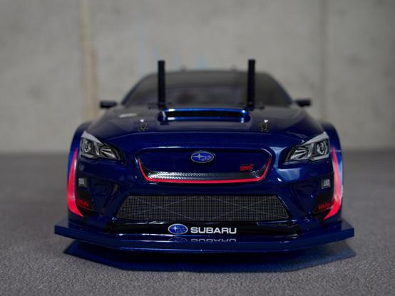 front low view of an RC car, painted in a metallic Blue with tinted windows, and markings of a Subaru WRX STI