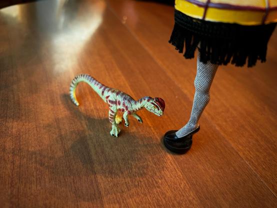 A green Dilophosaurus with brown spots stands beside the iconic sexy leg lamp from “A Christmas Story.”