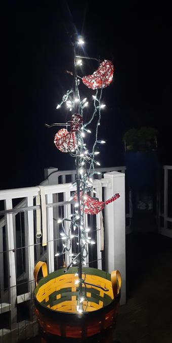 Beaded red birds in a metal tree with white string lights.