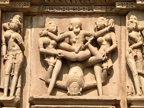 Das Foto zeigt eine erotische Szene mit drei Frauen und einem Mann am Kandariya Mahadeva  Temple aus dem 11. Jahrhundert in Khajuraho. 