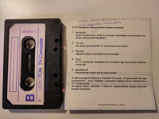 The B Side of the cassette has a white label, but it's empty/unlabelled. The back side of the case label lists the demonstration programs included, which are: Intro, Sliding Puzzle, Paint, Music, and Font maker. The top of the label also has remains of a stamp, that shows it was the inventory of the elementary school.