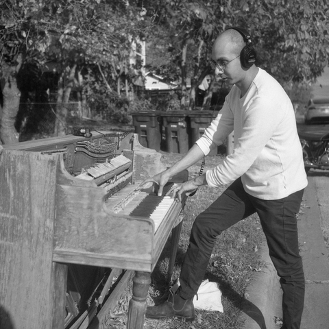 A black and white film photo. Juan, an artist, is recording audio from an abandoned piano in East Austin, Texas. Saturday, November 30, 2024.