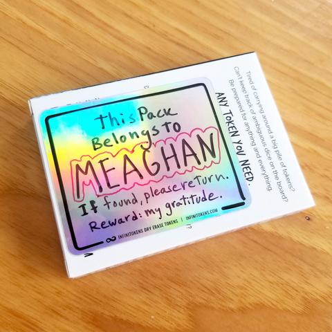 A pack of InfiniTokens dry erase tokens with a holofoil label on the back that says "This pack belongs to MEAGHAN. If found, please return. Reward: My gratitude."