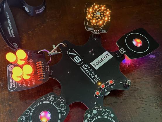 Showing off my Supercon badge with three TouchWheelSAOs plugged in, as well as the "number of supercons attended" SAO with 7 hilariously large LEDs soldered in, and the cool spiral petal LED SAO that was the other official SAO by Voja.