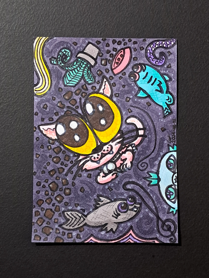 Un dessin représentant un chat rose avec d'énormes yeux et une clochette aux traits déformés, flottant dans de l'espace composé de croquettes, d'un bol, d'une plante herbachat turquoise, d'un tentacule violet, de poissons bizarres bleus et gris avec des yeux très gros, et d'autres choses.
