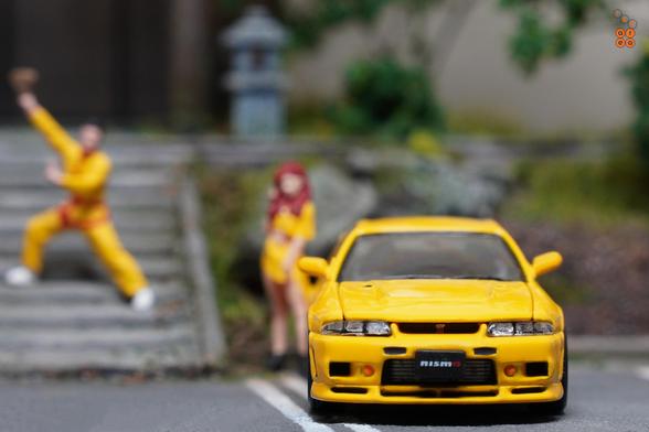 A front side of Nissan Skyline GT-R (R33) Nismo 400R Yellow by Pop Race in 1:64 scale with 1:64 figures on AREA 164