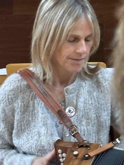 Sharon Shannon playing her button box while wearing an &quot;Instrument of Peace&quot; badge with a green and orange Irish flag bellows.