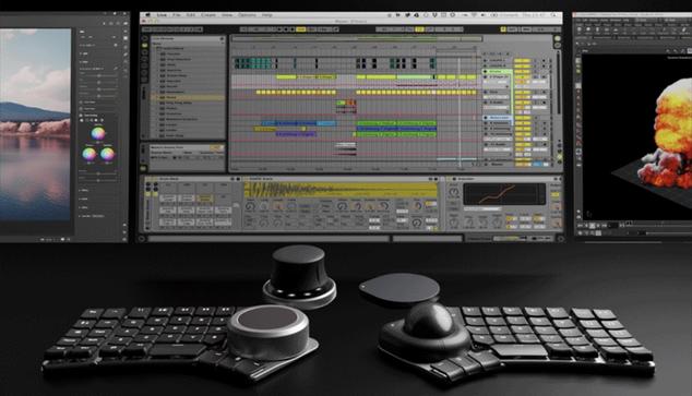 Naya Create split ergonomic keyboard in front of video editing screens. It is a non-traditional computer keyboard split into two halfs for right and left hands. Each side has a place by the thumb to put a trackball or trackpad, or 3D space mouse joystick.