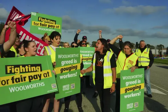 Warehouse workers, wearing “high-viz” safety vests,
( members of the United Workers Union) are on strike at Woolworths … they chant and raise their arms to the sky, hold clenched “solidarity” fists.
UWU signs
Fighting for Fair Pay at Woolworths 
Woolworths greed is gouging workers.