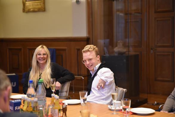 Two people sit at a laid table and smile. 