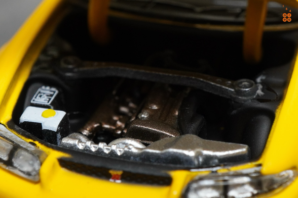 A close-up shot of Nissan Skyline GT-R (R33) Nismo 400R Yellow by Pop Race in 1:64 scale with 1:64 figures on AREA 164