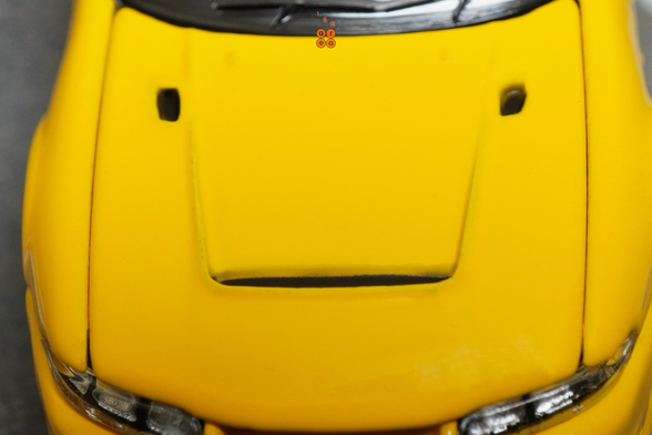 A close-up shot of Nissan Skyline GT-R (R33) Nismo 400R Yellow by Pop Race in 1:64 scale with 1:64 figures on AREA 164