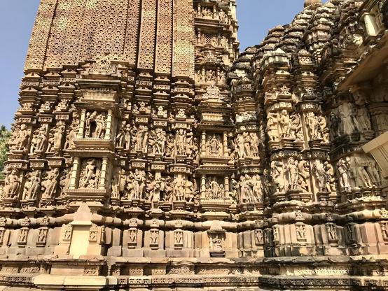 Das Foto zeigt die mit Figuren besetzte Außenfassade des Tempelturms vom Vamana Tempel aus dem 11. Jahrhundert in Khajuraho.