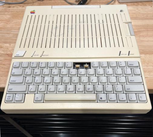 Apple Iic computer on the workbench. It is missing two keys from the keyboard: the 7 and the 8.