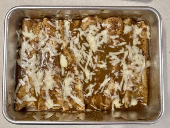 A pan full of turkey enchiladas, with Monterey Jack cheese on top. 