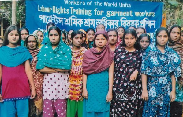 Text on a banner behind assembled women garment workers.

Workers of the world unite
Labour Rights Training for Garment Workers 