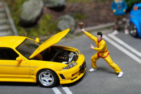 A guy in yellow suit and Nissan Skyline GT-R (R33) Nismo 400R Yellow by Pop Race in 1:64 scale with 1:64 figures on AREA 164