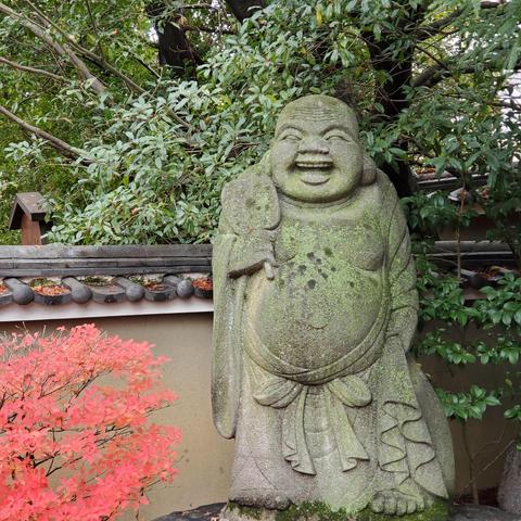 Statue of Hotei enjoying autumn leaves in the grounds of Daihoon-ji.