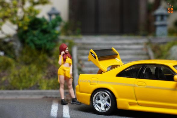 A female in yellow suit and Nissan Skyline GT-R (R33) Nismo 400R Yellow by Pop Race in 1:64 scale with 1:64 figure on AREA 164