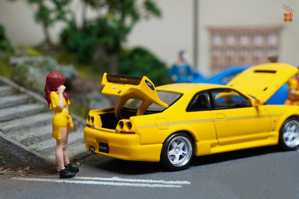 A female in yellow suit and Nissan Skyline GT-R (R33) Nismo 400R Yellow by Pop Race in 1:64 scale with 1:64 figure on AREA 164