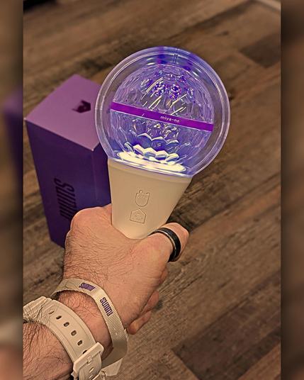 photo of a hand holding a kpop cheering lightstick (sunmi version).
it is a white handle with a disco ball on top.