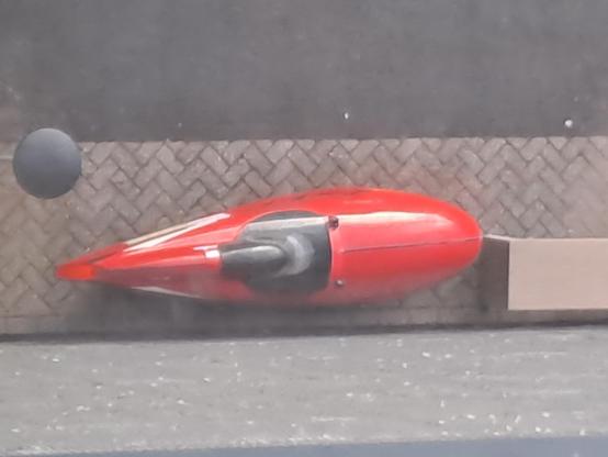 Rode quest velomobiel #387 van bovenaf gezien. Met zwarte racekap op straatstenen ondergrond
